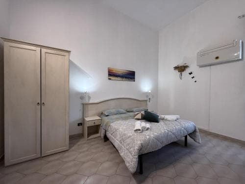 A cozy bedroom with a neatly made bed, patterned tiles, and soft lighting creates a serene atmosphere, ideal for travelers seeking a comfortable stay in a charming accommodation.