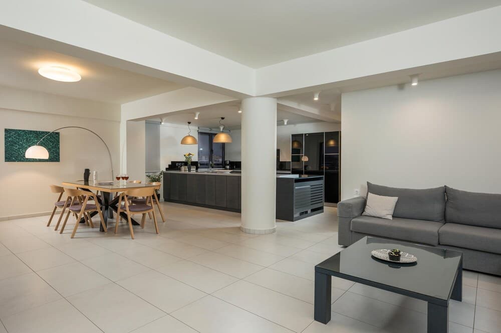 A modern, spacious apartment features an open-concept living area with sleek furniture, warm lighting, and a minimalist design, ideal for travelers seeking a stylish urban retreat.