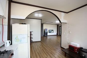 A cozy apartment interior features wooden floors, an arched doorway leading to a hallway, and modern appliances like a refrigerator and microwave, ideal for travelers seeking a comfortable stay in a quiet urban setting.