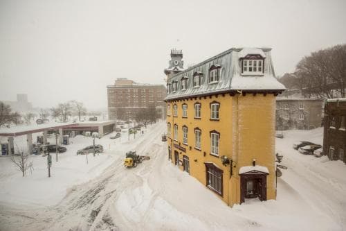 A picturesque yellow building with snow-covered rooftops stands out in a serene winter town scene, ideal for travelers seeking cozy accommodations amidst a tranquil snowy landscape.