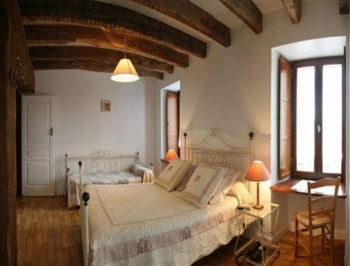 A cozy bedroom with rustic wooden beams, soft lighting, and a comfortable bed invites travelers seeking a charming and relaxing European retreat.