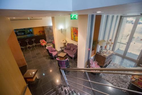 A cozy hotel lobby with vibrant purple seating, modern decor, and large windows inviting natural light, creates a welcoming atmosphere ideal for travelers seeking comfort and style during their stay.