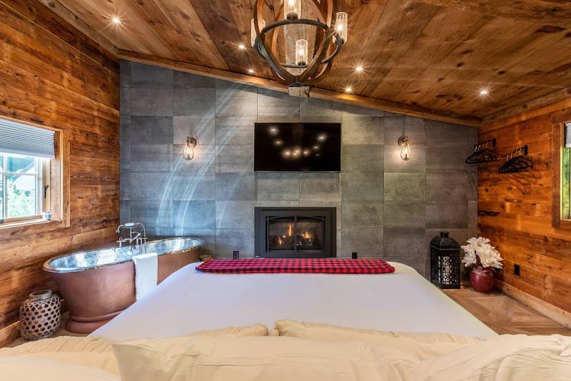 A cozy rustic retreat at the Barnstead Inn features a warm fireplace, a luxurious copper bathtub, and a charming wooden interior, perfect for a romantic getaway in Manchester Center, VT.