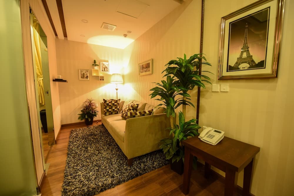 A cozy hotel lounge features warm lighting, a plush sofa adorned with patterned cushions, a vibrant potted plant, and an Eiffel Tower artwork, creating an inviting atmosphere ideal for travelers seeking relaxation.