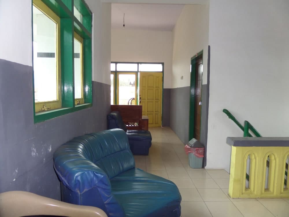 A quiet waiting area with blue leather sofas, green-framed windows, and tiled floors offers a simple yet functional space for travelers to relax before their journey.