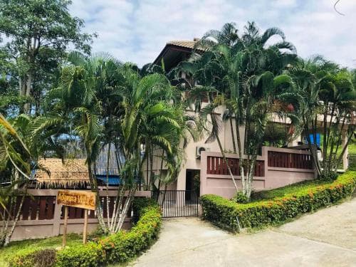 A serene tropical resort entrance framed by lush palm trees and vibrant greenery invites travelers seeking relaxation and natural beauty.