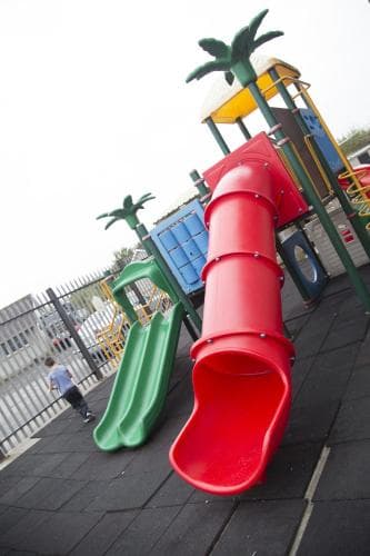 A vibrant playground featuring colorful slides and palm tree structures offers a cheerful and safe environment for children's outdoor fun, ideal for family-friendly travel destinations.
