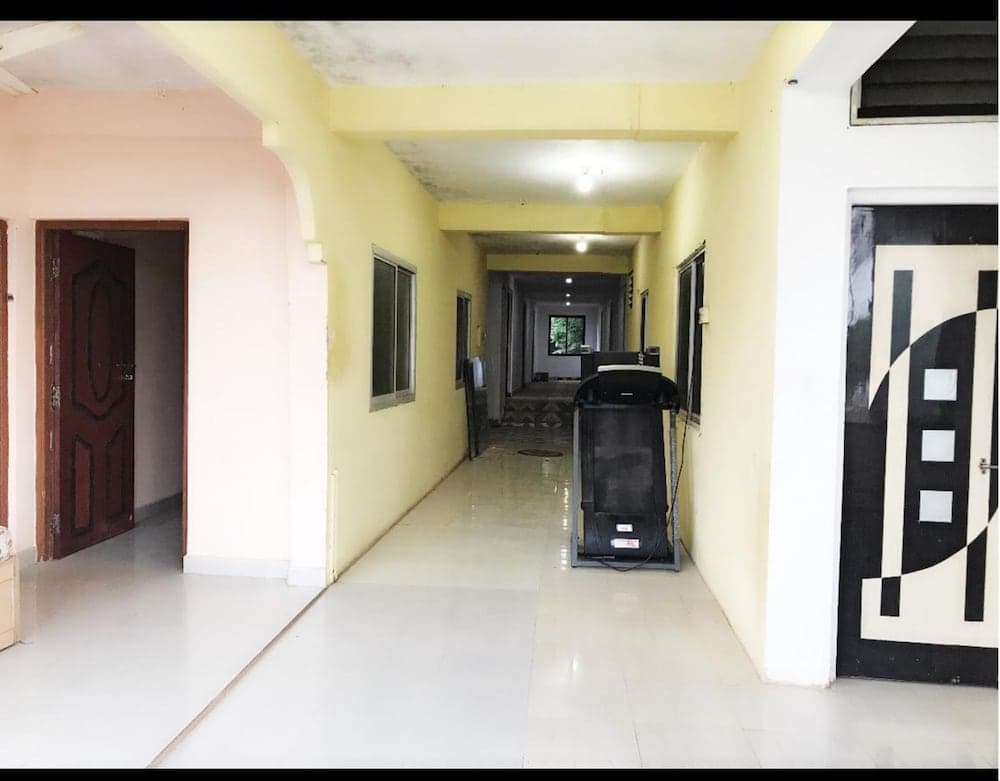 A serene hotel corridor with yellow walls, tiled floors, and a treadmill in the center offers a tranquil atmosphere ideal for travelers seeking relaxation and fitness during their stay.