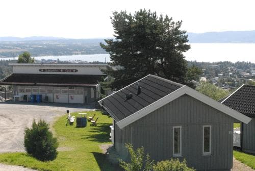 A serene lakeside retreat features modern cabins nestled among lush greenery, with a distant view of calm waters and hills, ideal for peaceful vacations and nature escapes.