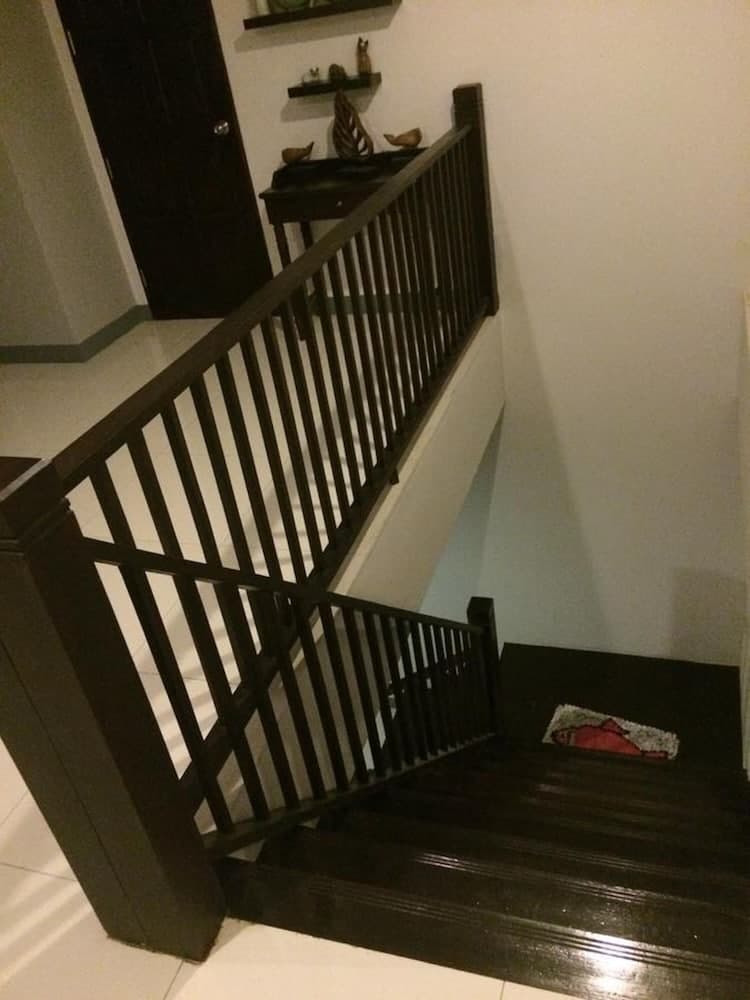 A cozy indoor staircase with dark wooden railings and steps leads to a warmly lit landing adorned with decorative shelves, ideal for travelers seeking a charming home stay experience.