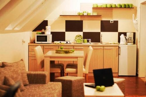 A cozy attic apartment kitchen with wooden furniture, vibrant green accents, and warm lighting creates an inviting atmosphere perfect for travelers seeking a comfortable self-catering stay.
