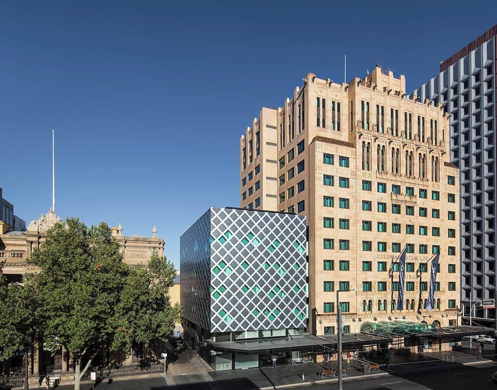 A vibrant urban scene showcases a historic building with Art Deco architecture juxtaposed against modern geometric structures under a clear blue sky, ideal for city exploration and architectural photography.