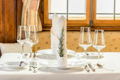 A cozy dining room table set with elegant glassware, neatly folded napkins adorned with rosemary sprigs, and soft natural light filtering through wooden-framed windows, evoking a serene and inviting atmosphere perfect for a romantic getaway or gourmet dining experience.