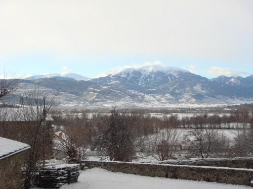 A serene winter landscape showcases snow-covered mountains overlooking a quiet village, ideal for tranquil retreats and nature photography.