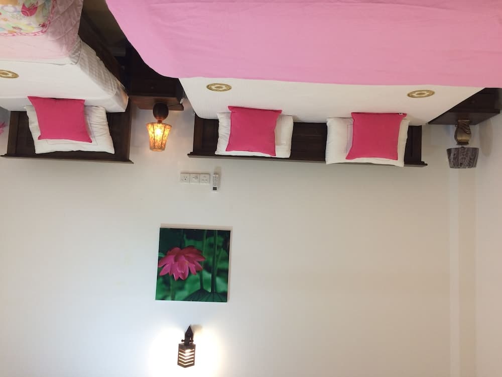 A cozy hotel room features bunk beds adorned with pink bedding, ambient wall lights, and a vibrant floral artwork, creating a warm and inviting atmosphere ideal for family travelers seeking comfort.