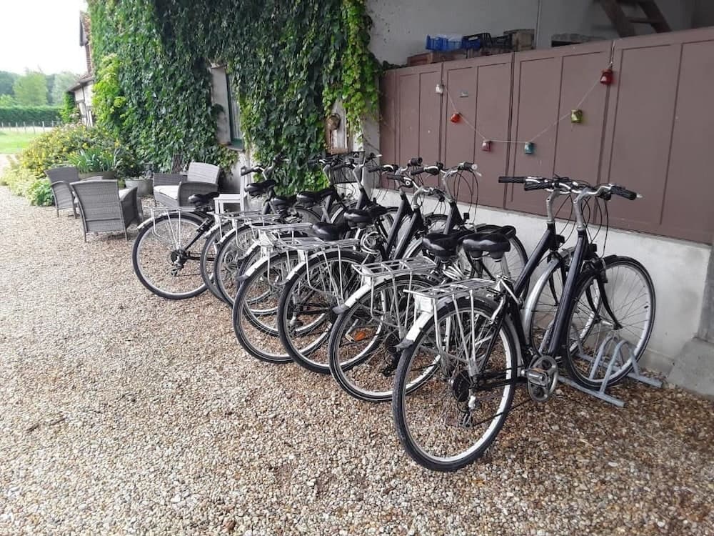 A serene outdoor setting features a row of bicycles parked neatly on gravel beside a rustic building adorned with ivy, ideal for travelers seeking a peaceful cycling adventure in a countryside retreat.