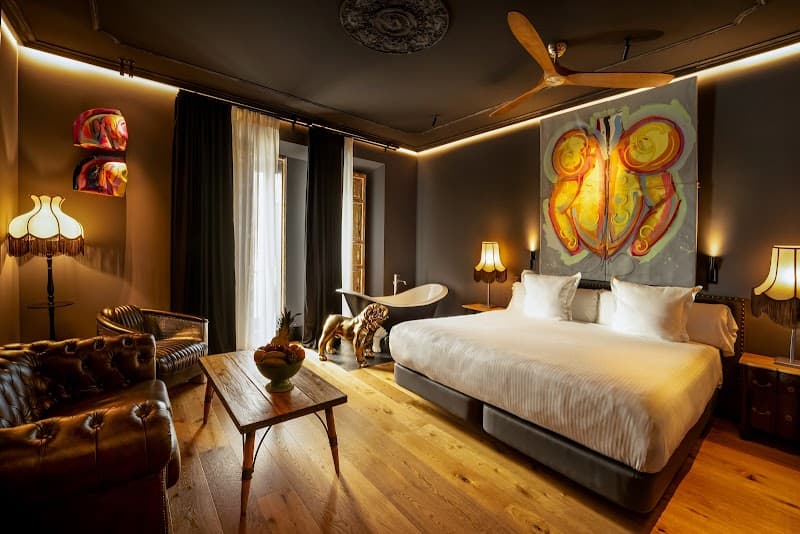 A cozy hotel lobby room in Sevilla's historic Casco Antiguo exudes warmth with its wooden floors, plush leather furniture, vibrant butterfly artwork, and soft lighting, ideal for travelers seeking a luxurious and intimate retreat.
