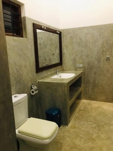 A cozy bathroom with textured walls, a wooden-framed mirror, and a sleek vanity offers a serene retreat, ideal for travelers seeking comfort in compact spaces.