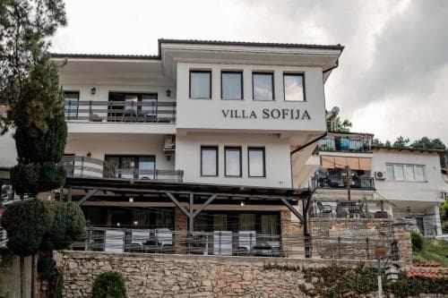 A serene two-story villa with balconies and lush greenery offers a cozy retreat, ideal for travelers seeking relaxation in a picturesque countryside setting.