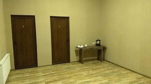 A cozy hotel hallway features two numbered wooden doors, a small table with tea service, and warm lighting, ideal for travelers seeking a quiet and welcoming accommodation.