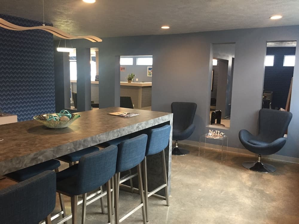 A modern, cozy lounge area features a sleek bar counter with blue stools, contemporary chairs, and stylish decor, ideal for travelers seeking a relaxing spot to unwind or socialize in a chic indoor setting.