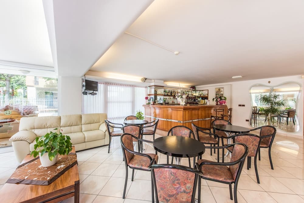 A cozy hotel lounge features modern furnishings, a well-stocked bar, and large windows letting in natural light, creating an inviting atmosphere ideal for travelers seeking relaxation or casual meetings.