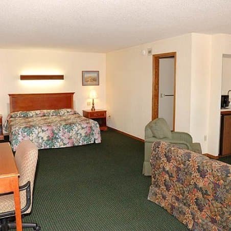 A cozy hotel room features floral-patterned bedding, a green armchair, and warm lighting, creating a welcoming atmosphere ideal for travelers seeking comfort during their stay.