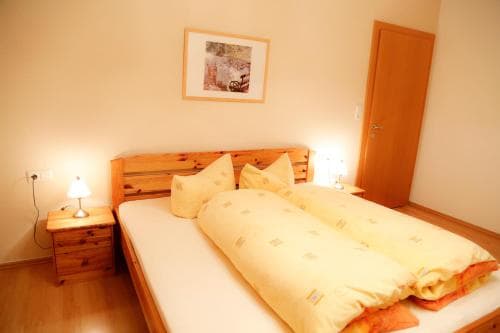 A cozy bedroom with wooden furniture, warm yellow bedding, and soft lighting creates an inviting atmosphere ideal for travelers seeking comfort and relaxation.