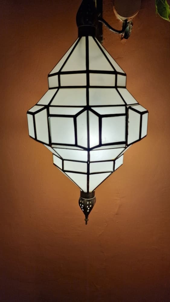 A geometrically patterned lantern casts a warm glow against a terracotta wall, creating an inviting ambiance ideal for travelers seeking cozy, culturally rich accommodations.