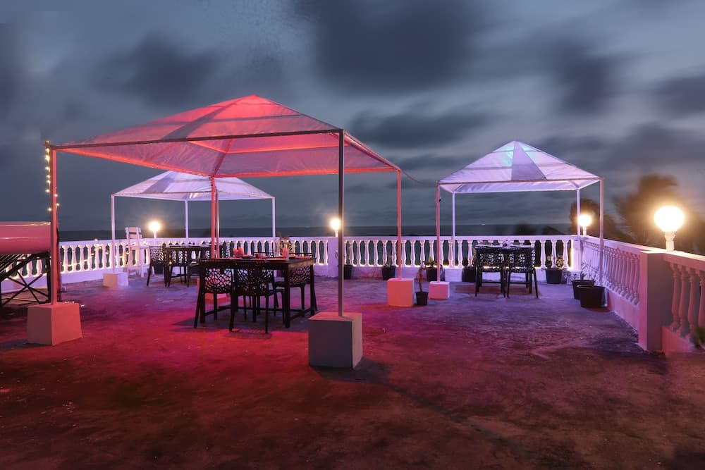 A serene rooftop dining area at dusk, featuring colorful umbrellas, cozy tables, ambient lighting, and an ocean view, perfect for romantic evenings or intimate gatherings.
