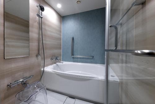 A modern bathroom with a sleek bathtub, glass shower enclosure, and minimalist decor offers a serene and luxurious retreat for travelers seeking comfort and cleanliness.