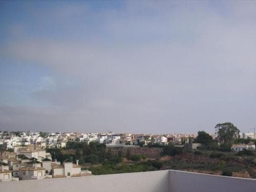 A serene view of a coastal town with white buildings nestled among greenery under a calm sky, ideal for travelers seeking relaxation and scenic vistas.