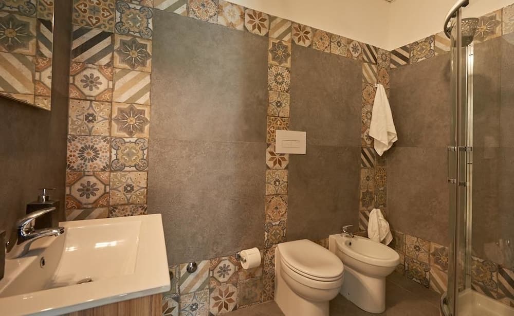 A cozy bathroom with ornate patterned tiles and modern fixtures exudes a warm, inviting atmosphere, perfect for travelers seeking comfort in boutique accommodations.
