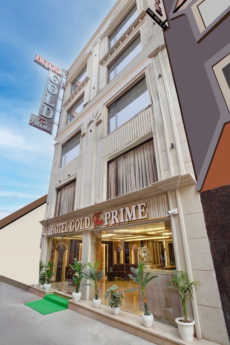 A welcoming urban hotel entrance adorned with potted plants and a bright signboard under a clear sky, ideal for travelers seeking comfortable accommodations in bustling New Delhi.