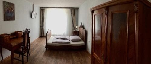 A cozy hotel room features wooden furnishings, soft natural light through sheer curtains, and a warm, inviting atmosphere ideal for travelers seeking comfort and relaxation.