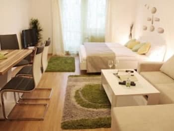 A cozy apartment living space features a modern sofa, dining area, and stylish decor with green accents, ideal for travelers seeking comfort and relaxation in an urban retreat.