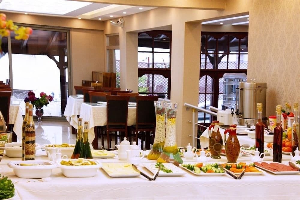 A warmly lit indoor dining area features an inviting buffet table laden with colorful dishes, decorative bottles, and fresh flowers, perfect for travelers seeking a cozy and well-catered meal experience.