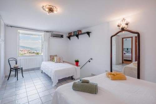 A cozy hotel room with tiled floors, two neatly made beds, a window offering scenic views, and warm lighting creates an inviting atmosphere ideal for travelers seeking comfort and relaxation.