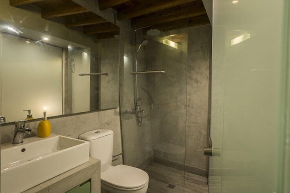 A cozy bathroom with rustic wooden beams, modern fixtures, and a glass-enclosed shower offers a serene retreat for travelers seeking comfort and style in their accommodations.