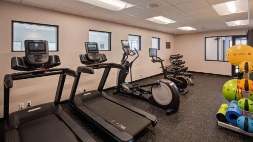 A well-lit indoor fitness center features treadmills, elliptical machines, and colorful exercise balls, creating an inviting atmosphere for travelers seeking a workout during their stay.