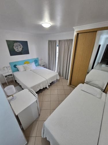 A cozy hotel room with two neatly made beds, a vibrant headboard painting, and soft lighting creates a welcoming atmosphere ideal for travelers seeking comfort and relaxation.