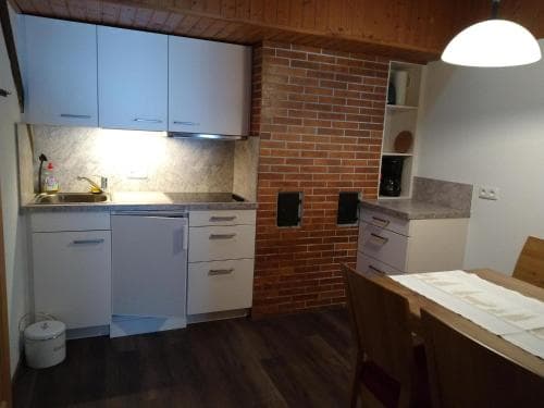 A cozy apartment kitchen with white cabinetry, a brick accent wall, and wooden flooring creates a warm and inviting atmosphere, ideal for travelers seeking a homey stay with modern amenities.