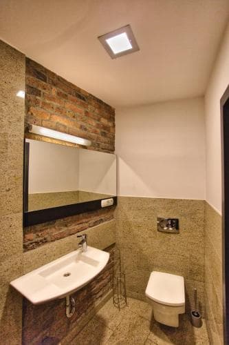 A cozy bathroom with exposed brick walls, modern fixtures, and warm lighting creates an inviting atmosphere, perfect for travelers seeking a stylish yet comfortable accommodation space.