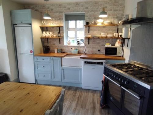 A cozy kitchen with rustic brick walls, wooden countertops, and blue cabinetry creates a warm and inviting atmosphere, perfect for travelers seeking a homey cooking experience.