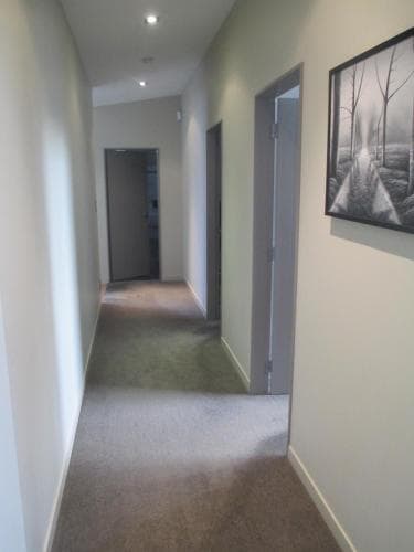 A cozy hotel hallway with carpeted floors, neutral walls, framed artwork, and soft lighting creates a welcoming atmosphere ideal for travelers seeking comfort and tranquility.