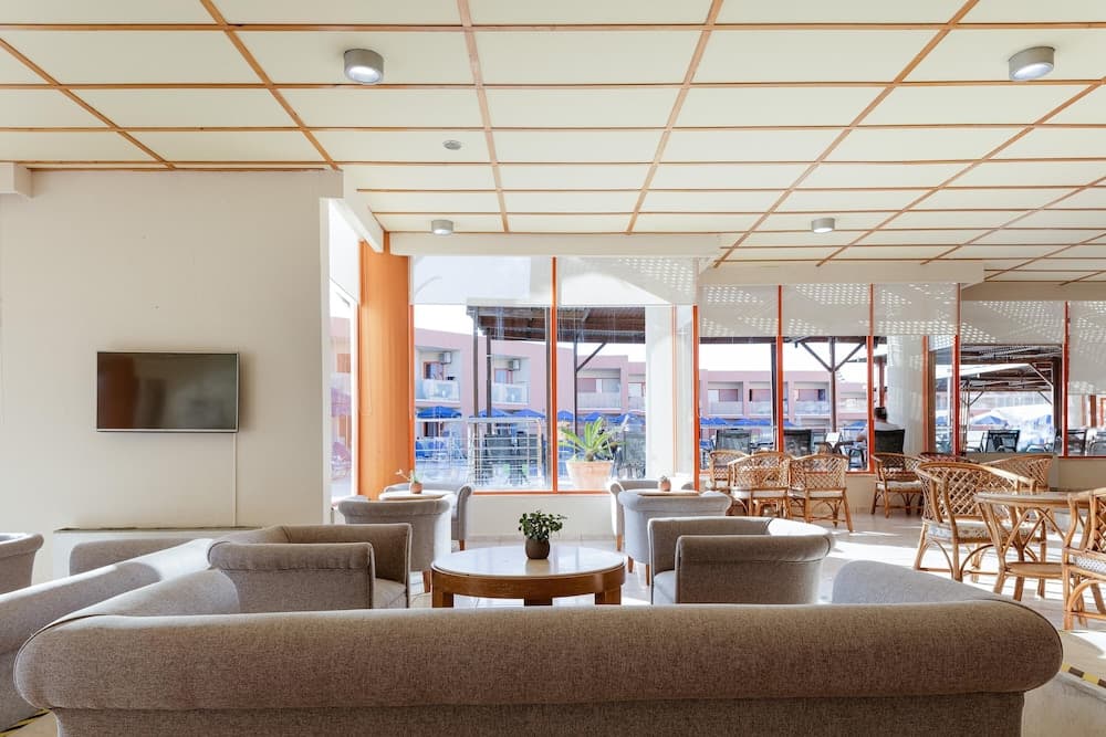 A cozy hotel lounge with plush sofas, wooden tables, and large windows offering a serene view of an outdoor patio area, ideal for travelers seeking relaxation and comfort.