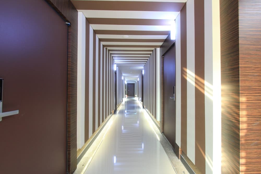 A sleek hotel corridor with modern striped walls, recessed lighting, and polished floors creates an inviting atmosphere ideal for travelers seeking comfort and style.