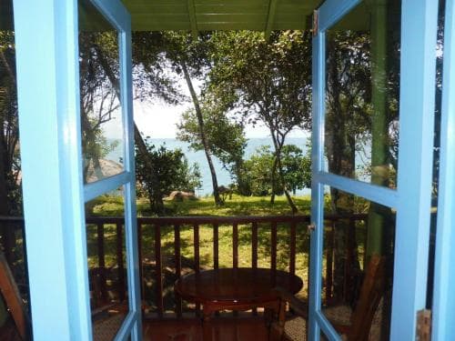 A serene coastal retreat framed by blue-framed doors reveals lush greenery and a tranquil ocean view, perfect for a relaxing getaway.