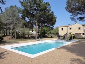 A serene outdoor scene features a tranquil pool surrounded by lush trees and a cozy villa, ideal for a relaxing vacation retreat.