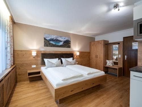 A cozy hotel room with wooden furnishings, a serene mountain artwork, and warm lighting creates an inviting atmosphere ideal for travelers seeking relaxation in a rustic retreat.